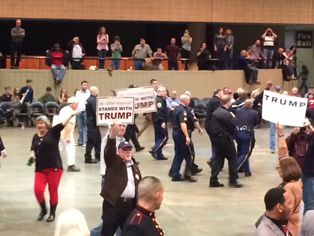 A protester is escorted out of the rally. 