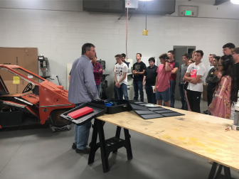 Students standing in the classroom with engineering teacher, Brian Copes, talking about their project for the 2018-2019 school year